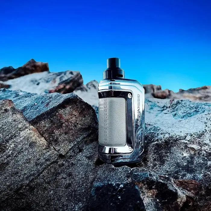 Metallic vaping device or e-cigarette positioned on rocky terrain.